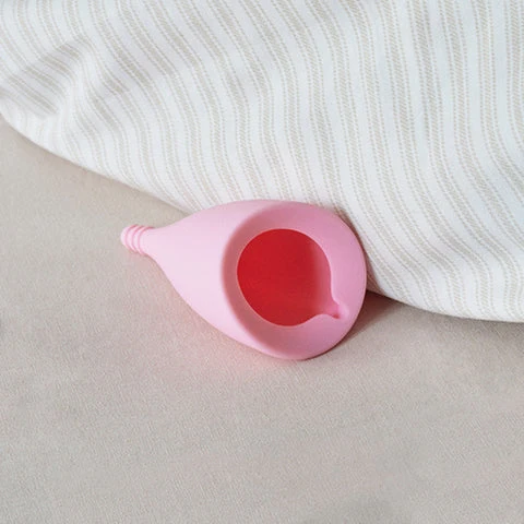 Intimina Lily Cup (Reusable Menstrual Cup) product image Intimina Lily Cup resting on its side next to a soft surface, highlighting its sleek and flexible form.